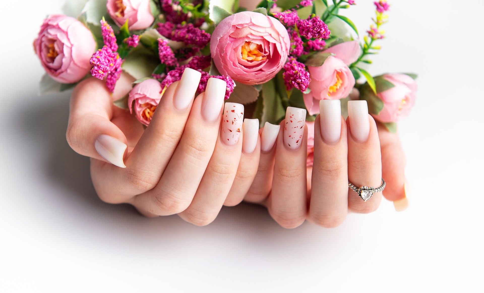 Woman showing stylish pink manicure holding pink flowers