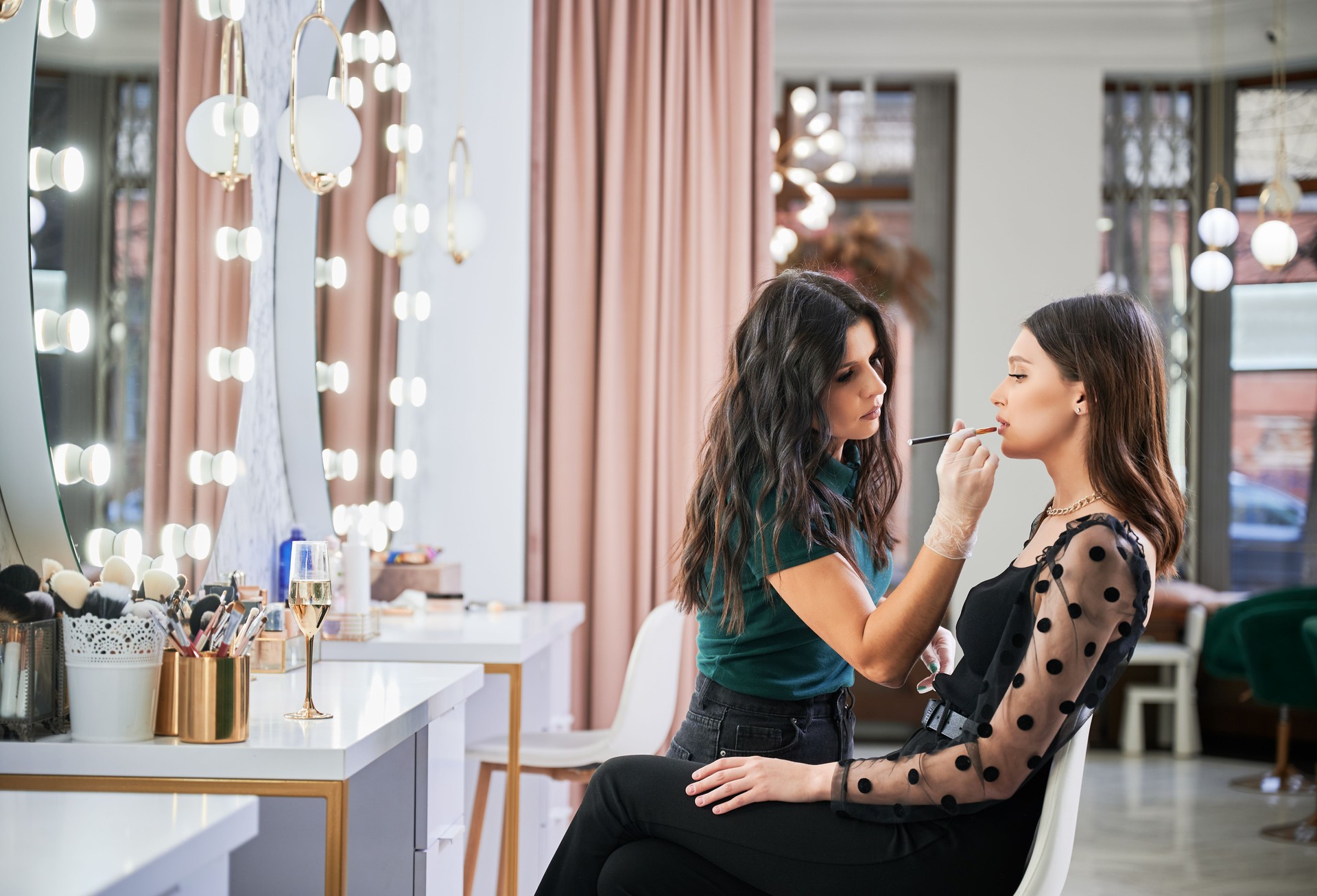 Smiling makeup artist doing makeup for woman in beauty salon.